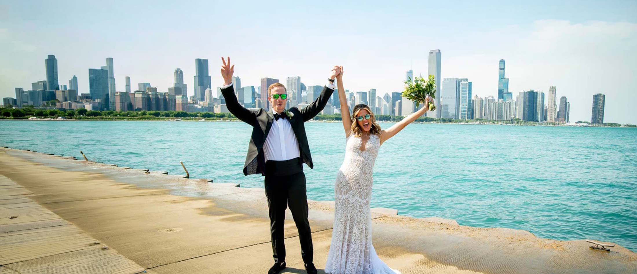 Bride and groom celebrating on the Chicago lakefront with the skyline behind them